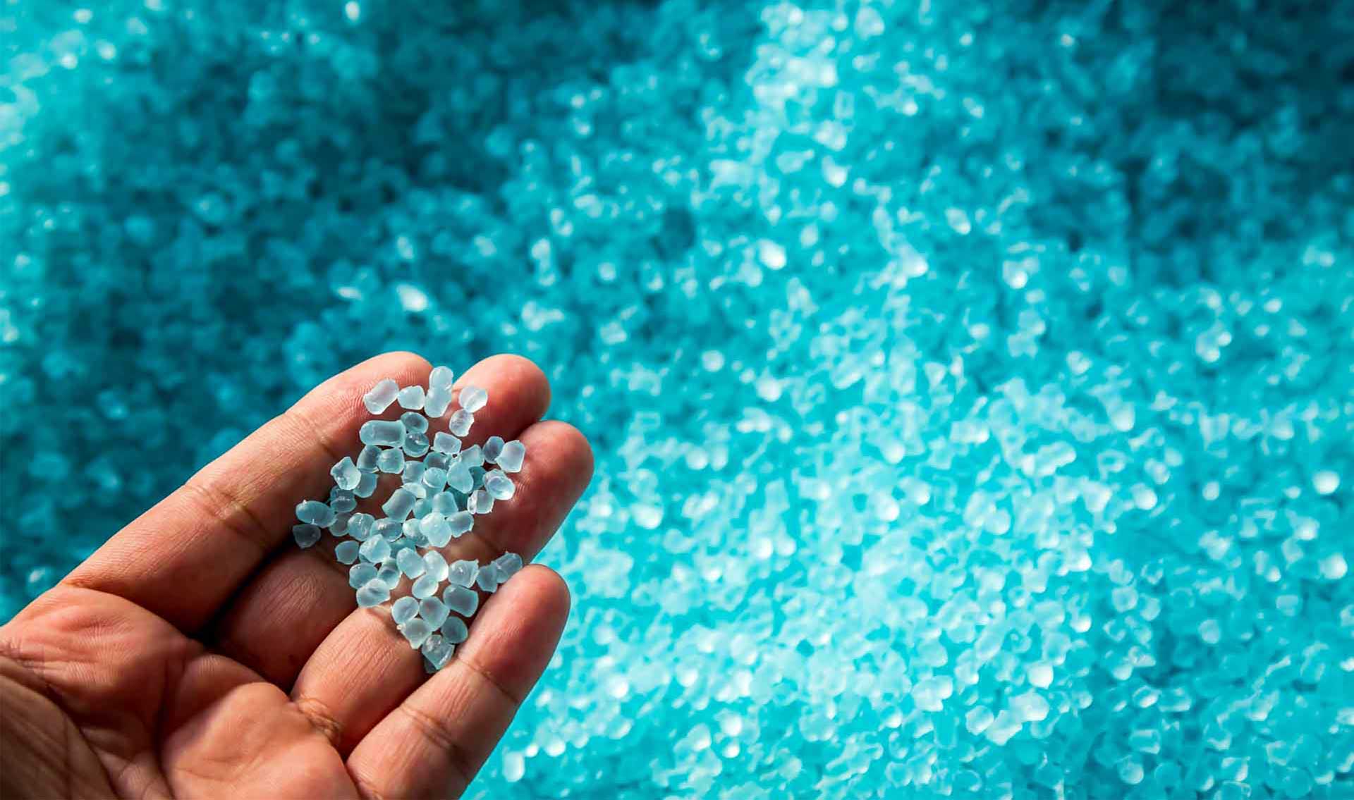 Hand-holding-blue-translucent-plastic-pellets